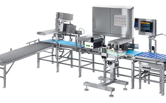 Scanvaegts Automatic Box Weigh Labelling systemer håndterer til automatisk vejning, print og påsætning af etiket på kartoner o. lign. produkter.
